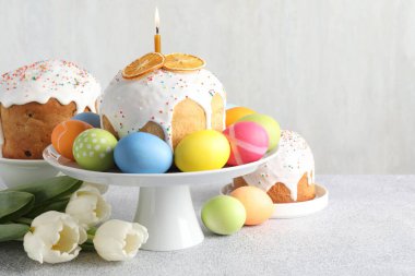 Lezzetli Paskalya pastaları, açık gri masada boyanmış yumurta ve laleler, metin için yer.