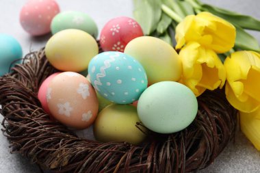 Yuvada boyanmış Paskalya yumurtaları ve masada güzel laleler, yakın plan.