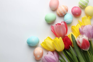 Boyalı Paskalya yumurtaları ve beyaz arka planda güzel laleler. Metin için boşluk