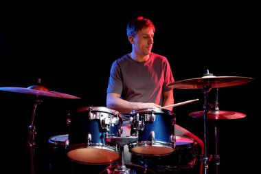 Siyah arkaplana karşı renk ışıklarıyla davul çalan adam