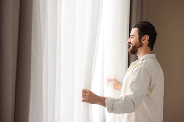 Evde şık pencere perdeleri açan adam