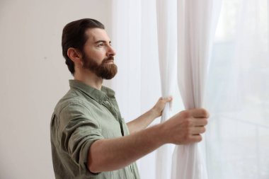 Evde şık pencere perdeleri açan adam