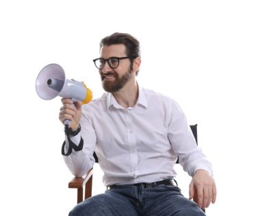 Profesyonel film yönetmeni, beyaz arka plana karşı sandalyede megafonla oturuyor.