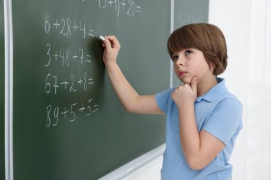 Okullu çocuk sınıfta tahtada matematik yapıyor.