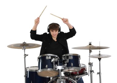 Kulaklıklı, bagetleriyle davul çalmayı öğrenen genç bir çocuk.