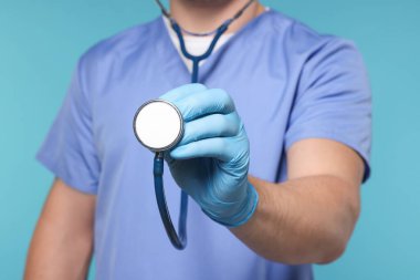 Açık mavi arka planda steteskobu olan doktor, seçici odak