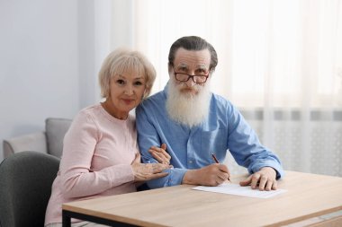 Ahşap masada son arzuları ve vasiyetnameleri imzalayan yaşlı çift.