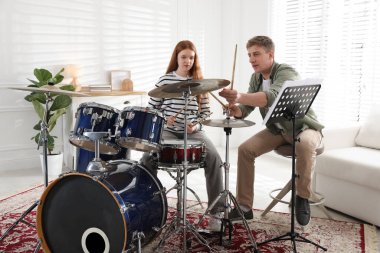 Genç kız içeride müzik öğretmeniyle bateri çalmayı öğreniyor.