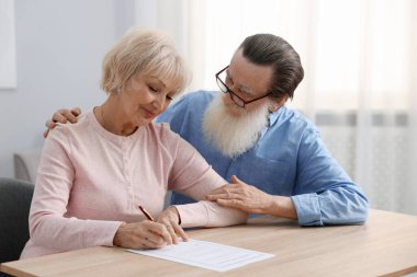 Ahşap masada son arzuları ve vasiyetnameleri imzalayan yaşlı çift.