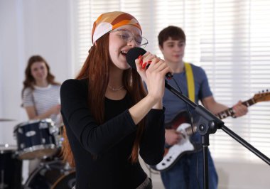 Genç müzik grubu içeride performanslarını prova ediyor.