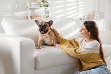 Evdeki kanepenin yanında tatlı köpeği olan bir kadın.
