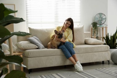 Evdeki kanepenin yanında tatlı köpeği olan bir kadın.