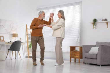 Mutlu yaşlı çift evde dans ediyor.