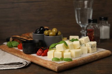 Tahta masada değişik peynir, zeytin ve fesleğen çeşitleri olan servis masası, yakın plan.