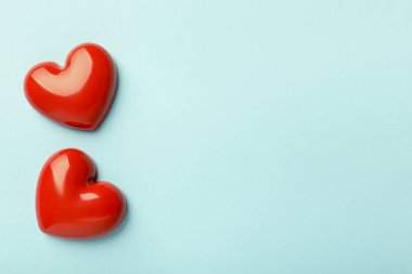 Açık mavi arka planda iki kırmızı dekoratif kalp, düz yatıyordu. Metin için boşluk