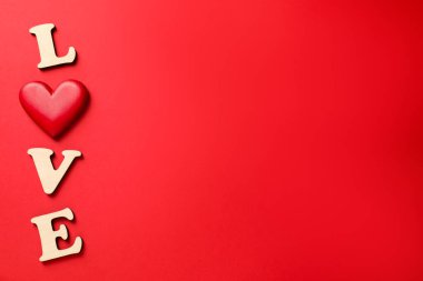 Aşk kelimesi ahşap harflerden ve kırmızı arka planda dekoratif kalpten yapılmıştır. Metin için boşluk