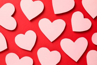 Sevgi. Kırmızı arka planda birçok pembe dekoratif kalp, düz yatıyordu.
