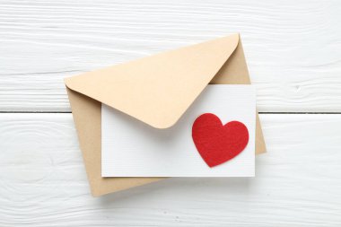 Sevgililer Günün kutlu olsun. Tebrik kartı ve dekoratif kalp ile beyaz ahşap masa, üst görünüm