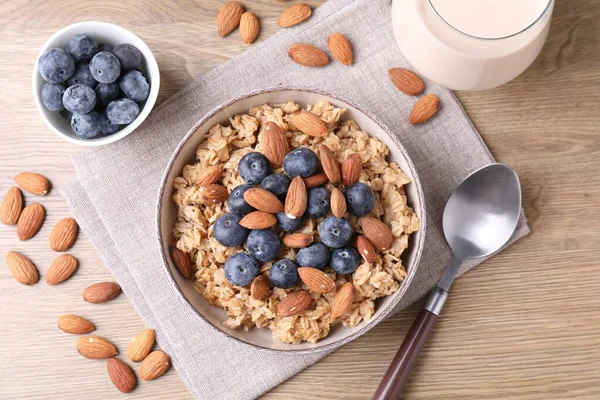 Bademli yulaf gevreği, yaban mersini ve süt ahşap masada, düz yerde.