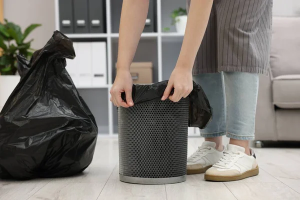 Kapalı alandaki çöp kutusuna plastik poşet koyan kadın.