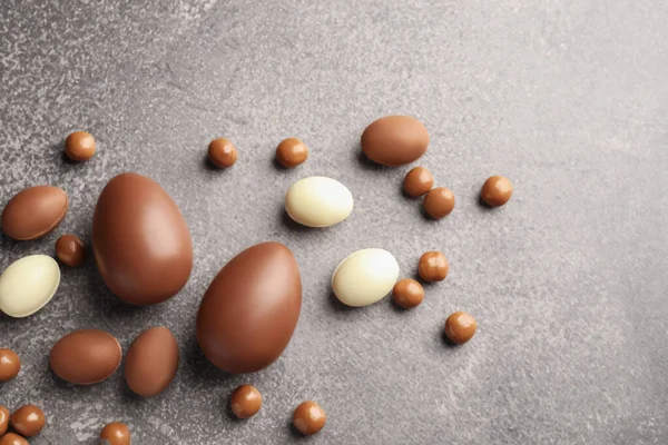 Paskalya kutlaması. Gri desenli masa üzerinde bir sürü çikolata yumurtası ve dragee, metin için boşluk ile düz yatıyordu.