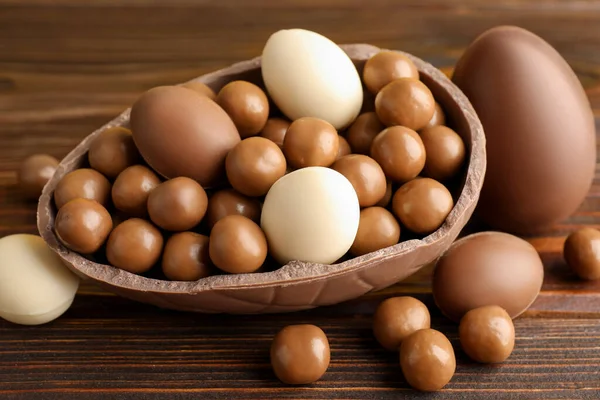 Ahşap masada şekerli çikolatalı yumurtalar, yakın plan. Mutlu Paskalyalar