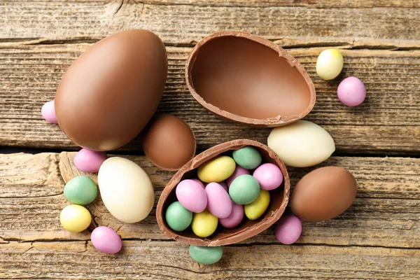 Tahta masanın üzerinde renkli şekerlemeli leziz çikolatalı yumurtalar, düz yatak. Mutlu Paskalyalar