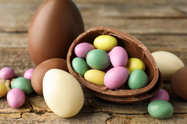 Ahşap masada renkli şekerlemeli lezzetli çikolata yumurtaları, yakın plan. Mutlu Paskalyalar