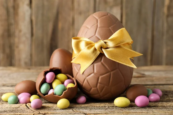 Ahşap masada renkli şekerlemeli lezzetli çikolata yumurtaları, yakın plan. Mutlu Paskalyalar
