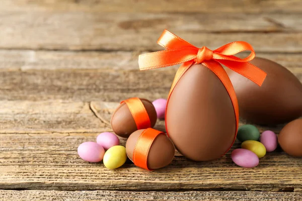 Mutlu Paskalyalar. Ahşap masada renkli şekerlemeli lezzetli çikolata yumurtaları, yakın plan. Metin için boşluk