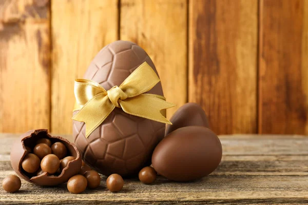 Mutlu Paskalyalar. Ahşap masada şekerli çikolatalı yumurtalar, yakın plan. Metin için boşluk