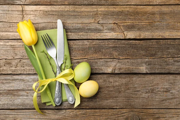 Paskalya sofrası. Lale ve ahşap arka planda boyanmış yumurtaları olan güzel gümüş takımlar, üst manzara. Metin için boşluk