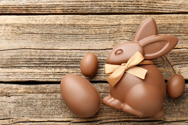 Çikolatalı Paskalya tavşanı ve yumurtalar ahşap masada, düz yatıyordu. Metin için boşluk