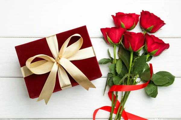 Güzel kadife hediye kutusu ve beyaz ahşap arka planda güller, düz yatış. Sevgililer Günü