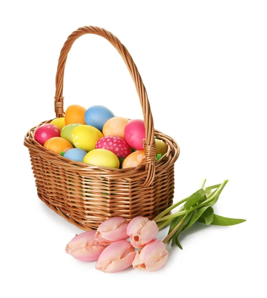 Hasır sepete boyanmış Paskalya yumurtaları ve beyaza izole edilmiş güzel laleler.