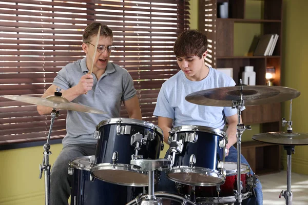 Genç çocuk içeride müzik öğretmeniyle bateri çalmayı öğreniyor.