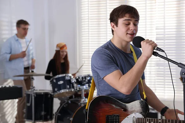 Genç müzik grubu içeride performanslarını prova ediyor.