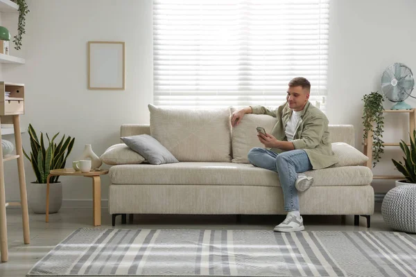 Evdeki kanepede dinlenen genç adam.