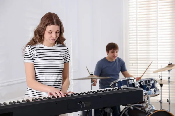 Genç müzik grubu içeride performanslarını prova ediyor.