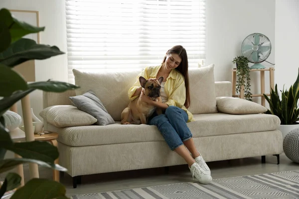 Evdeki kanepenin yanında tatlı köpeği olan bir kadın.