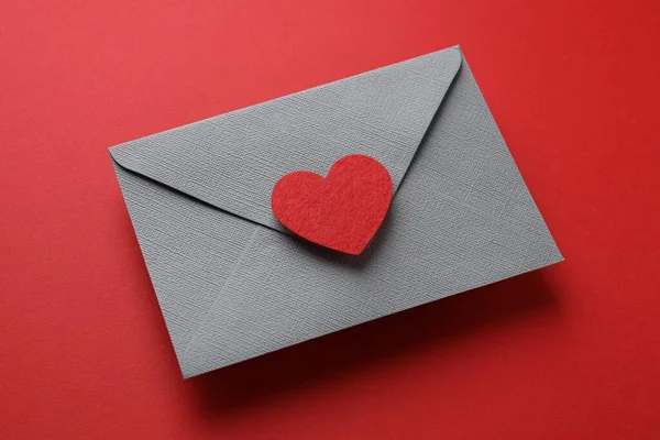 Sevgililer Günün kutlu olsun. Tebrik kartı ve kırmızı arka planda dekoratif kalp ile zarf, yakın plan