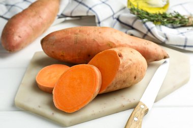 Çiğ patates ve bıçak beyaz ahşap masada, yakın plan.