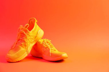 Turuncu arka planda şık bir çift spor ayakkabı. Metin için boşluk