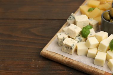 Tahta masada değişik peynir, zeytin ve fesleğen içeren servis masası, yakın çekim. Metin için boşluk