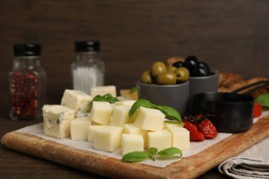 Tahta masada değişik peynir, zeytin ve fesleğen çeşitleri olan servis masası, yakın plan.