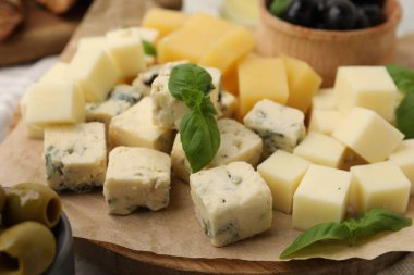 Masada değişik peynir, zeytin ve fesleğen çeşitleri olan servis masası, yakın plan.