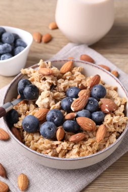 Bademli yulaf gevreği, yaban mersini ve süt ahşap masada, yakın plan.