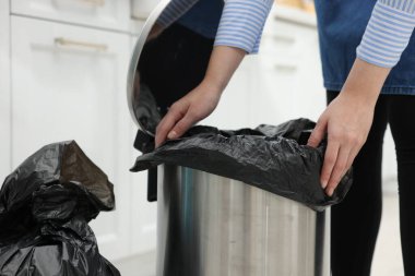 Mutfaktaki çöp kutusuna plastik poşet koyan kadın, yakın plan.
