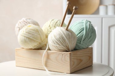 Örgü iplikleri ve iğneler kapalı bir masa üzerinde sandıkta, yakın plan.