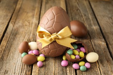 Ahşap masada renkli şekerlemeli lezzetli çikolata yumurtaları, yakın plan. Mutlu Paskalyalar